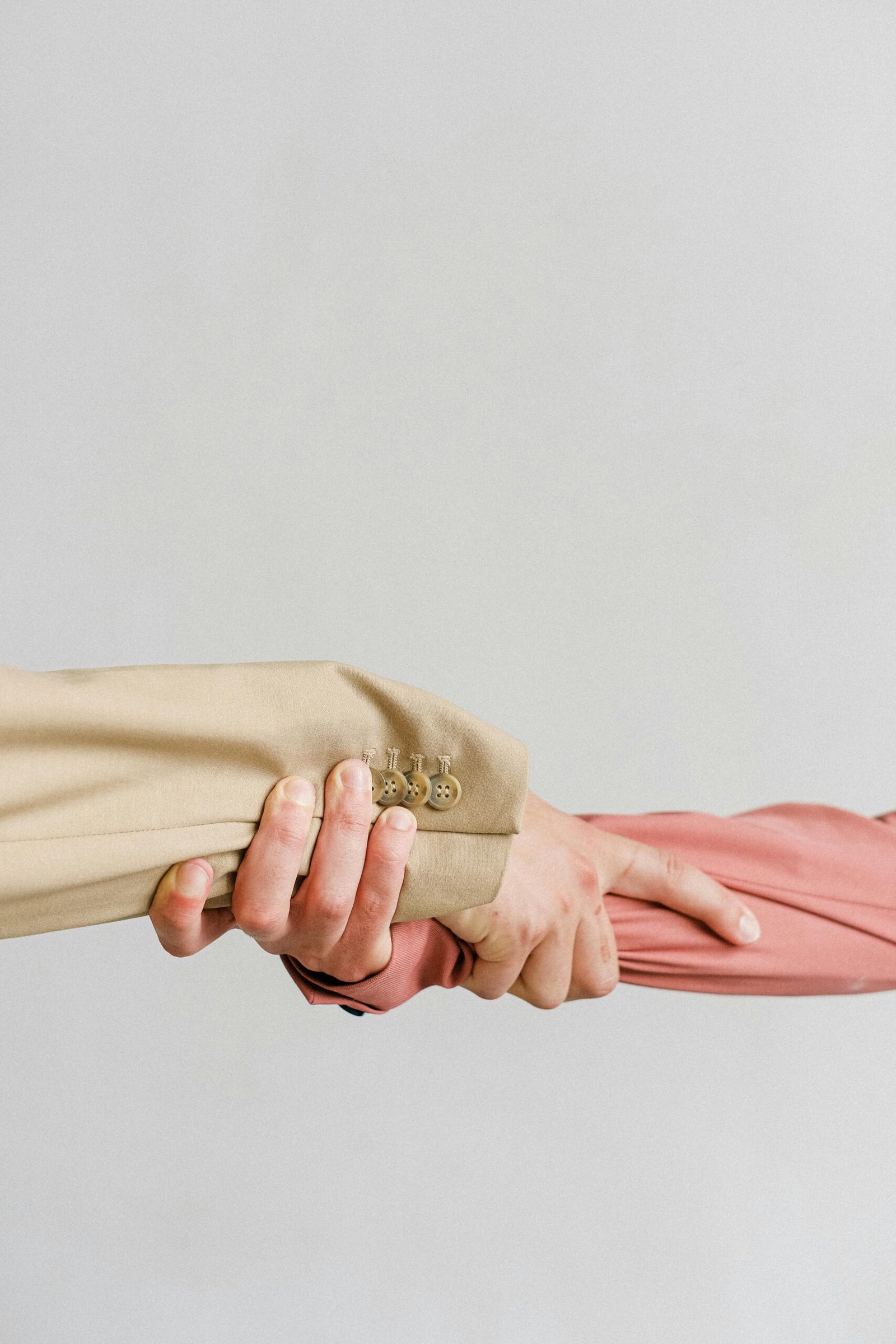 Two hands in formal attire grasping each other, symbolizing unity and support.